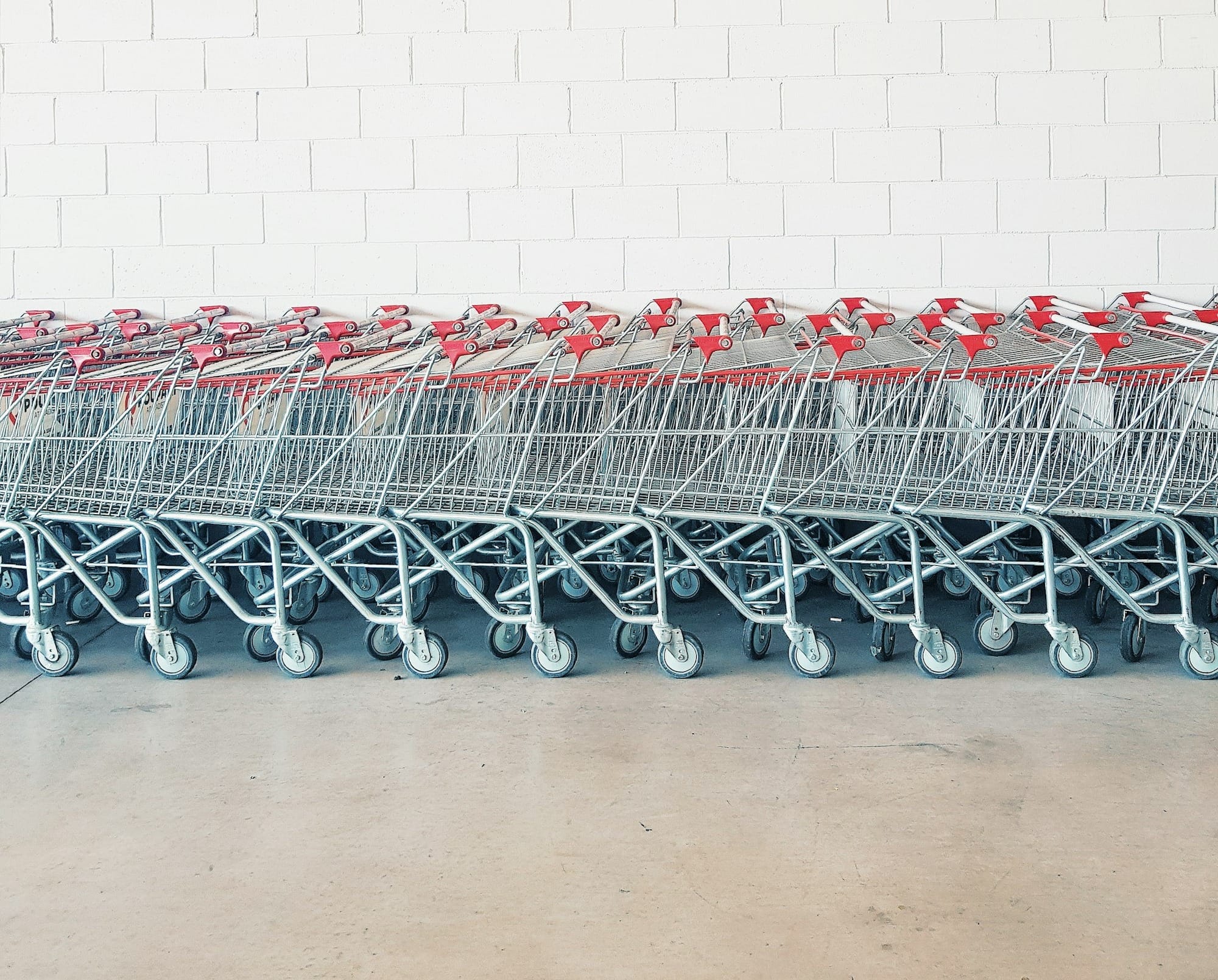 gray-and-red metal shopping cart lot beside wall