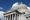 A Baroque dome and columned facade photographed against a blue sky with a couple of fluffy white clouds.