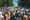 A large crowd marking on a tree-lined street, photographed from behind. Signs in the crowd read "Keep your laws off my body" and "U.S. out of my uterus."