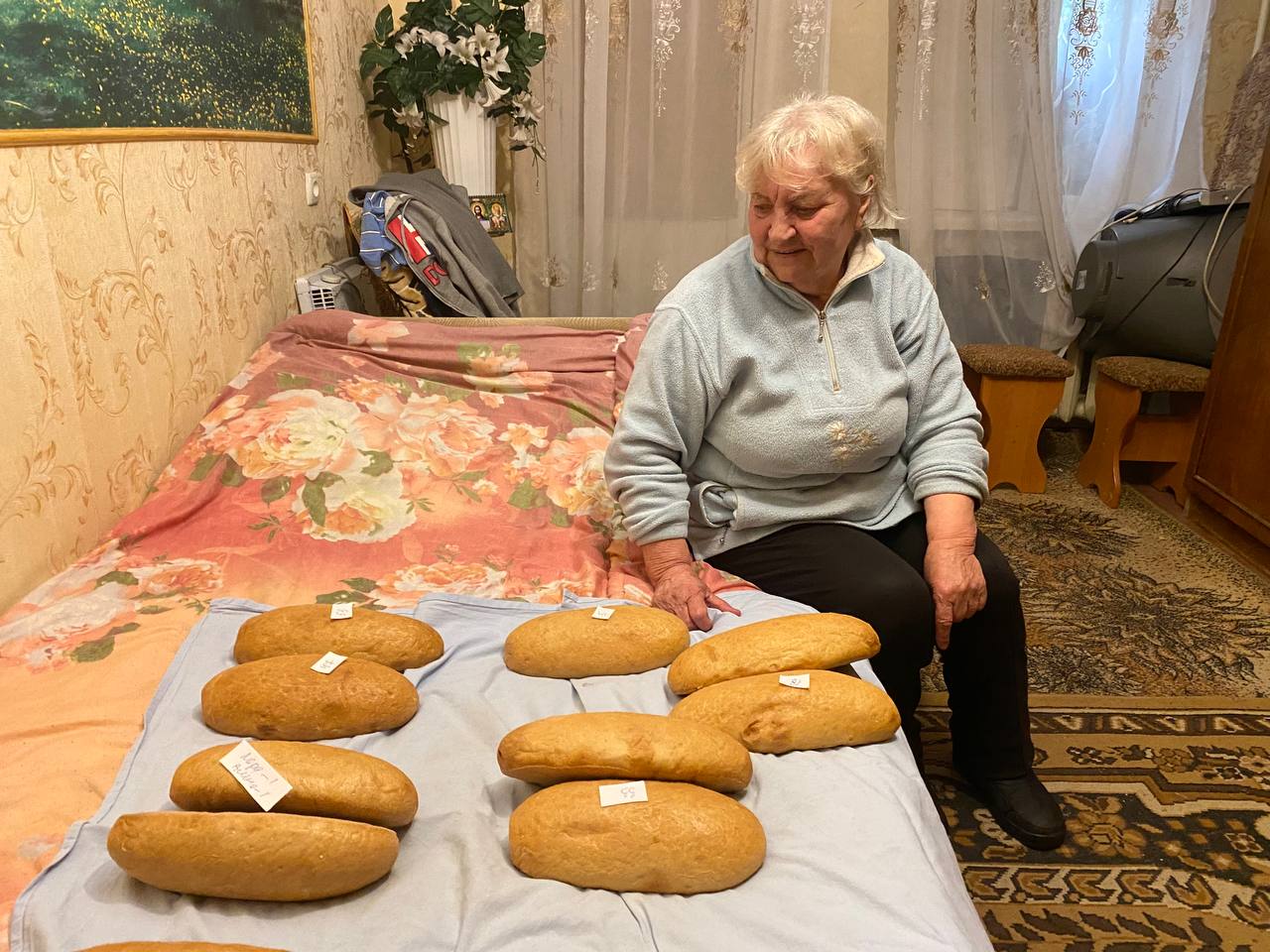 Александра Павловна Казначеева с гуманитарной помощью. На каждом батоне записка с номером квартиры или именем — кому передать. Фото: Елена Костюченко