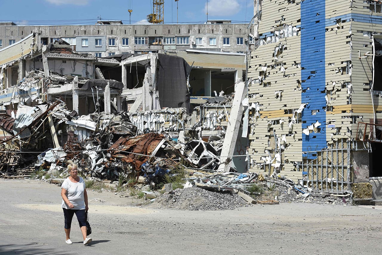Женщина проходит мимо разрушенного здания в Мариуполе.