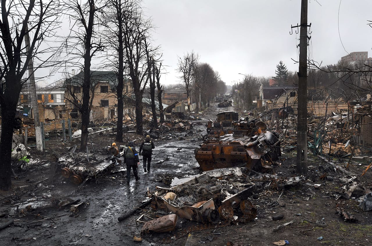 Украинские полицейские идут между разбитой военной техникой в Киевской области, Украина. 