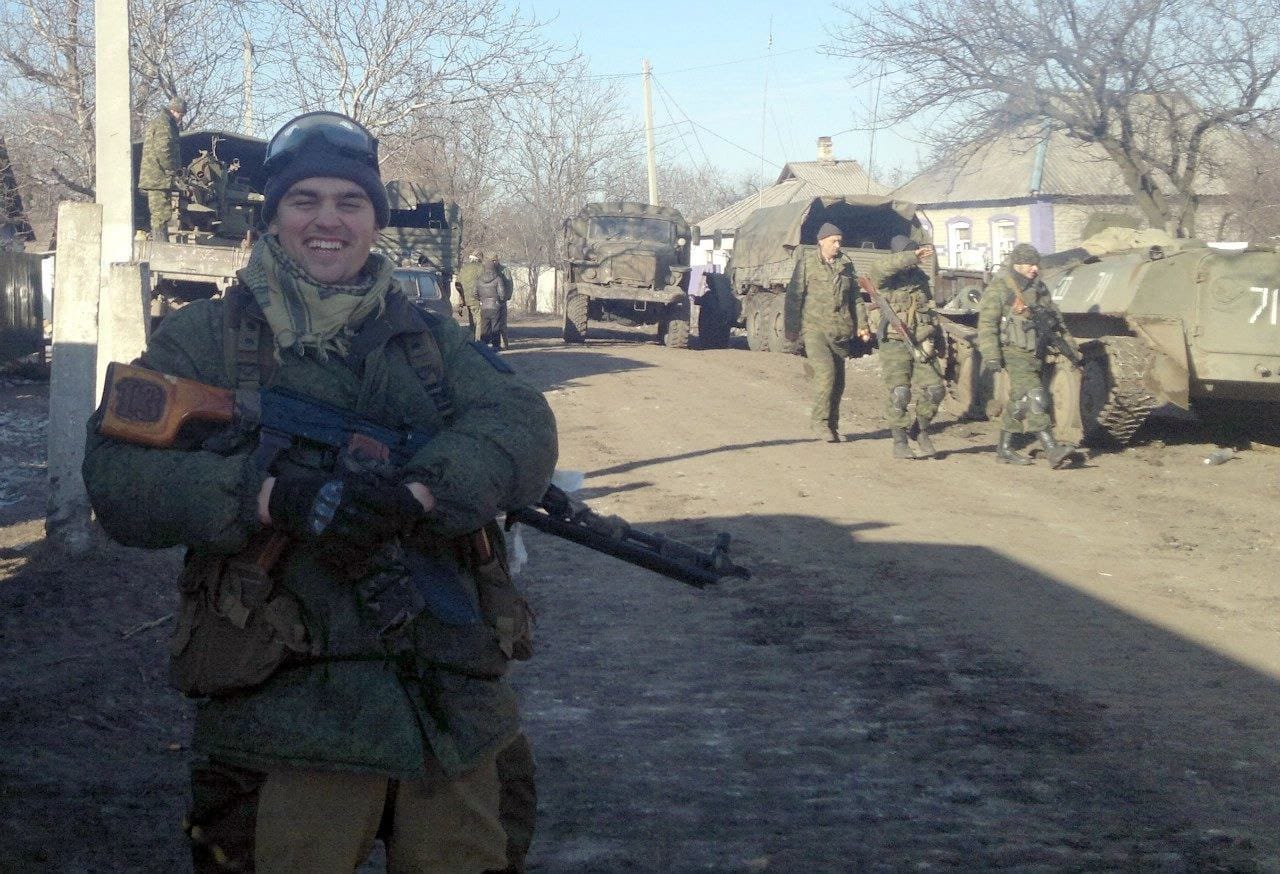 Тринадцатый с винтовкой в руках на фоне военных