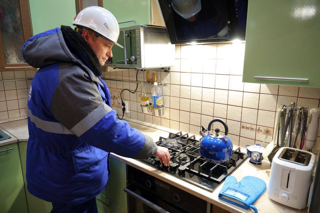 Сотрудник газовой службы проверяет кухонную плиту