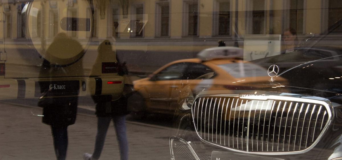 Мерседес, которые теперь импортирует контрабанда, за стеклом витрины, в отражении — улица и люди