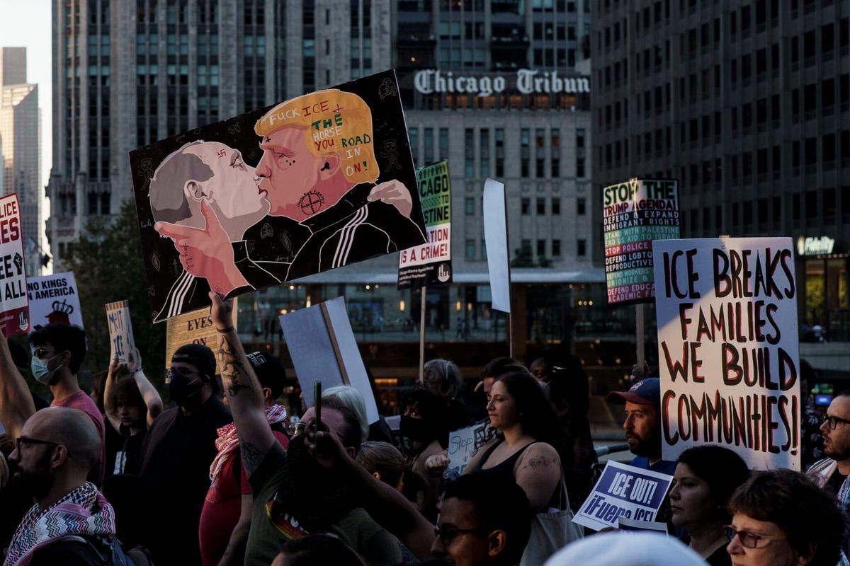 Плакат, изображающий поцелуй Путина и Трампа, на демонстрации в Чикаго
