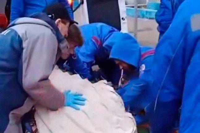 Сотрудники скорой помощи поднимают пациентку в машину