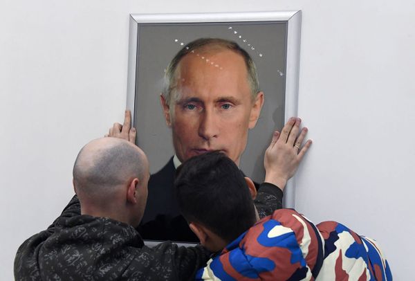 Портрет Путина вешает на стену
