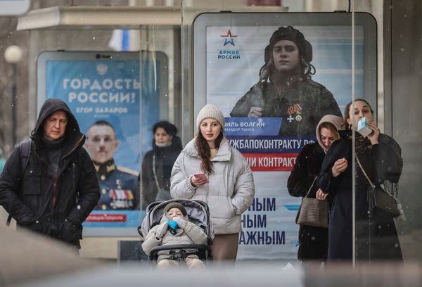 Люди на остановке с рекламой военной службы в Москве