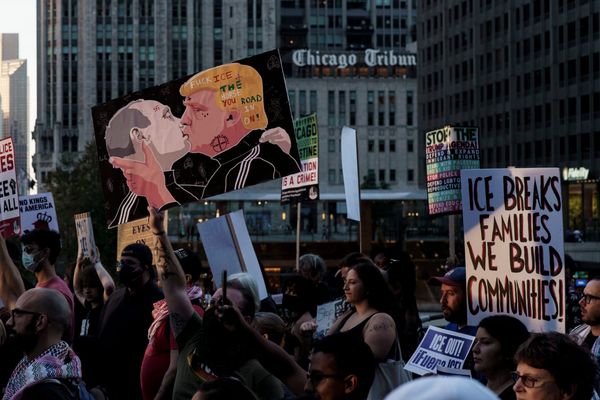 Плакат, изображающий поцелуй Путина и Трампа, на демонстрации в Чикаго