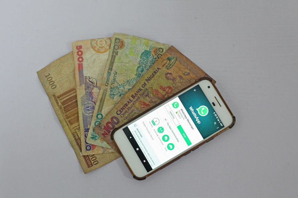 A smartphone lying beside naira banknotes in Lagos, Nigeria, evoking mobile money transfers.