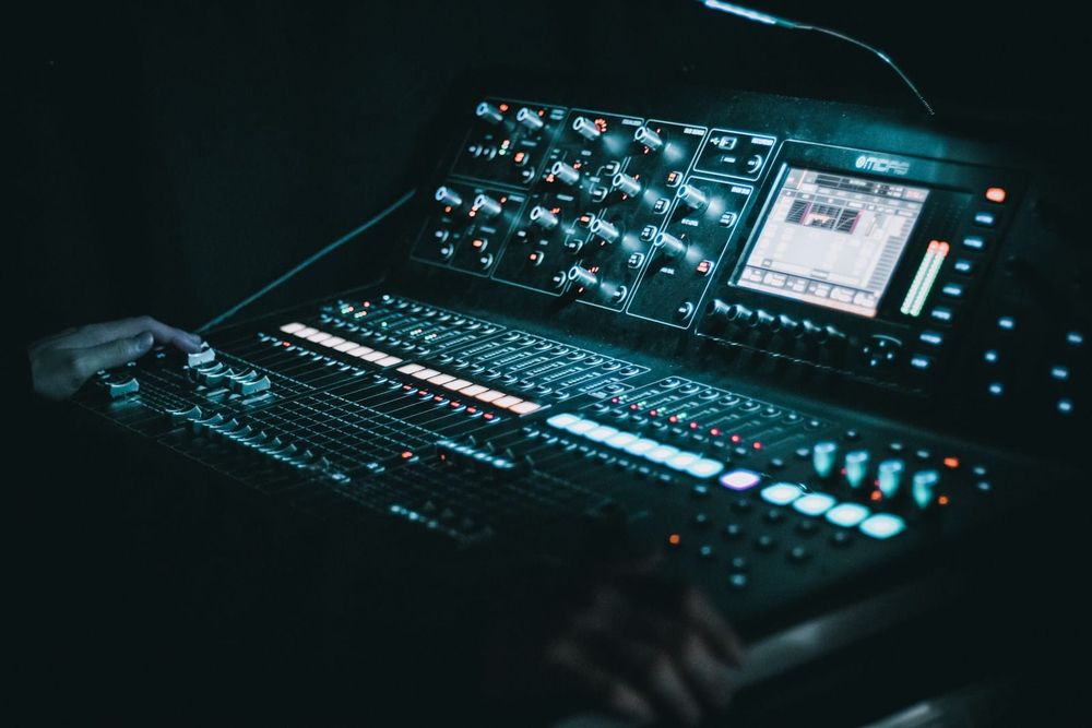 A professional audio mixing console glowing in dim light, its controls illuminated during a session.
