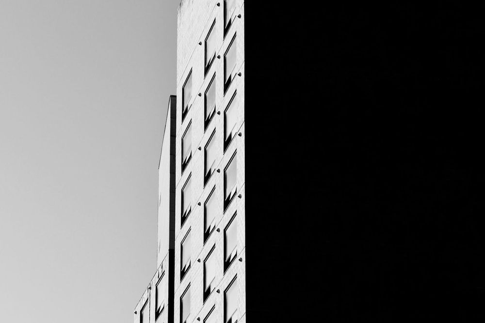 A minimalist black-and-white building facade fills the frame, its repetitive grid of windows and concrete bands reading like an abstract bar chart.
