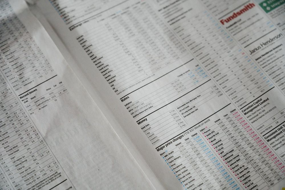 Close-up of the finance section of a newspaper, columns of small printed figures in charcoal ink on pale paper.