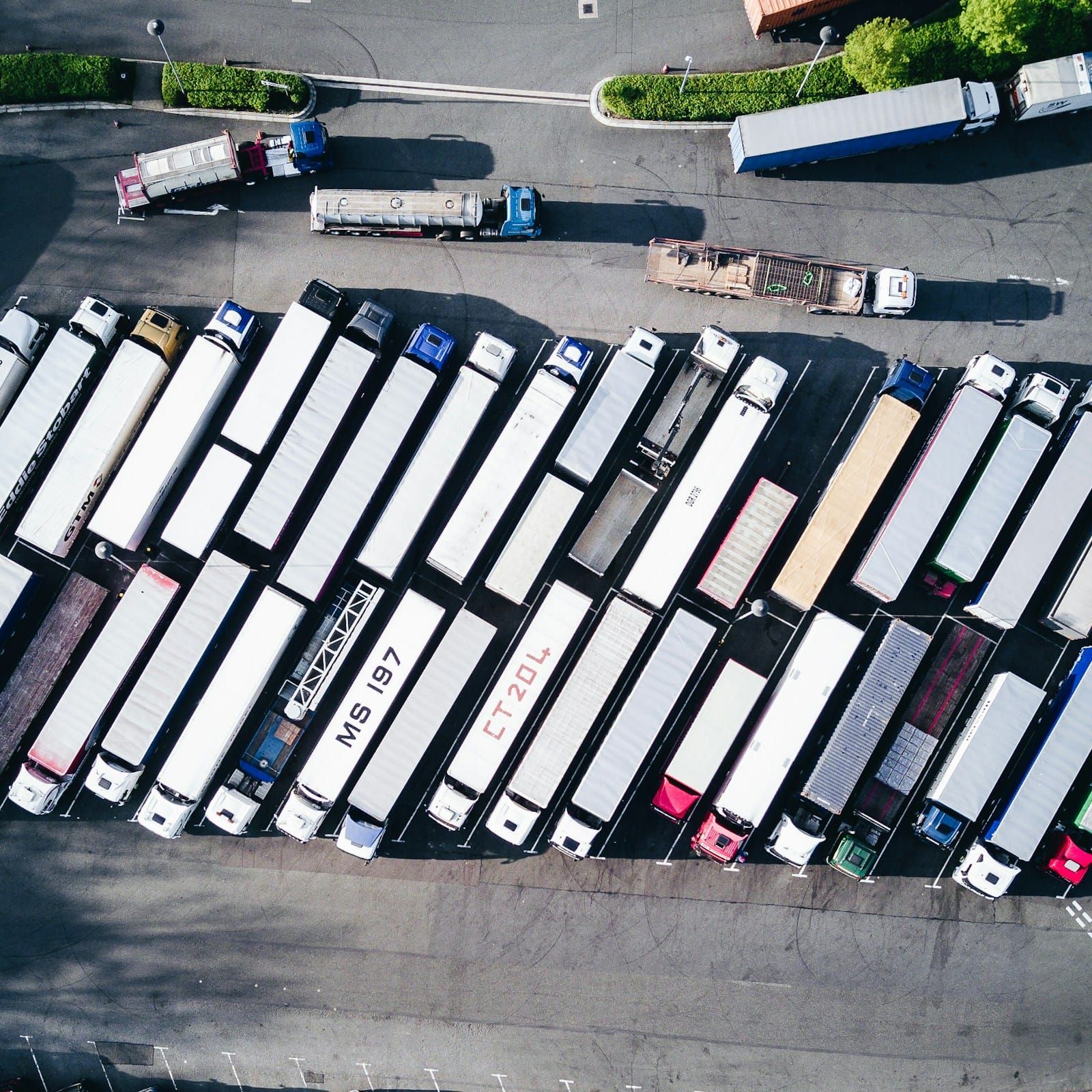 Aerial view of freight lorries parked in tight ordered rows across a large truck yard.