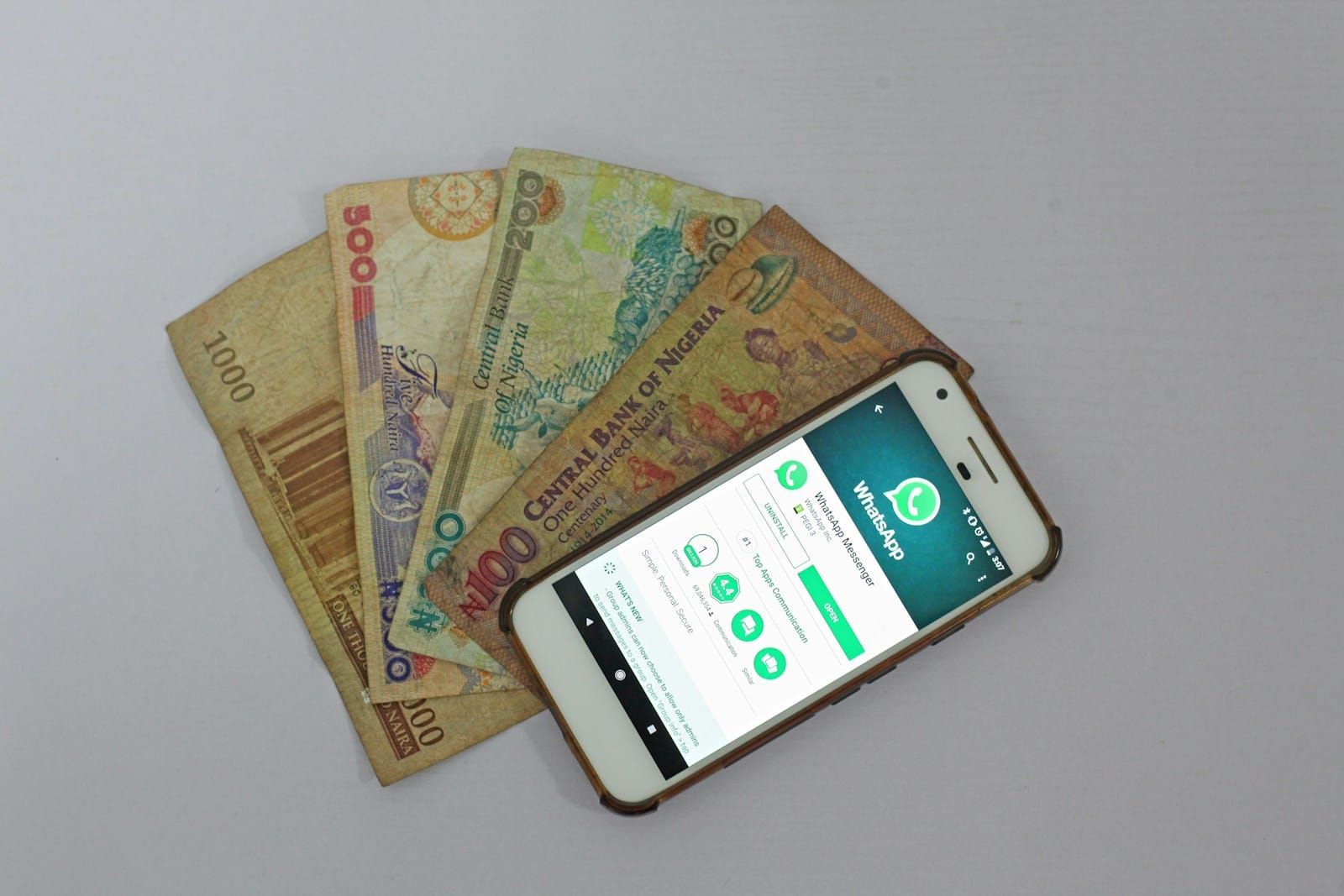 A smartphone lying beside naira banknotes in Lagos, Nigeria, evoking mobile money transfers.