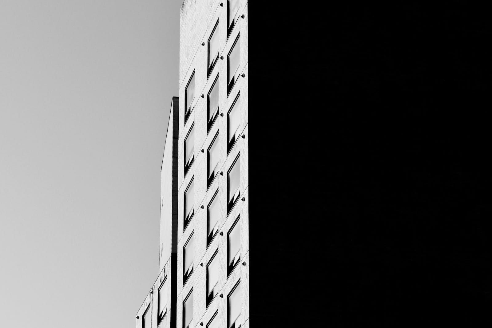 A minimalist black-and-white building facade fills the frame, its repetitive grid of windows and concrete bands reading like an abstract bar chart.