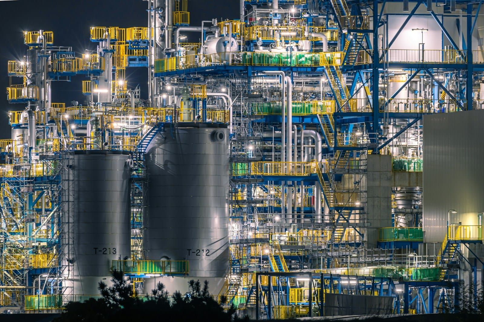 An industrial oil refinery with towers and pipework lit up against the night sky.