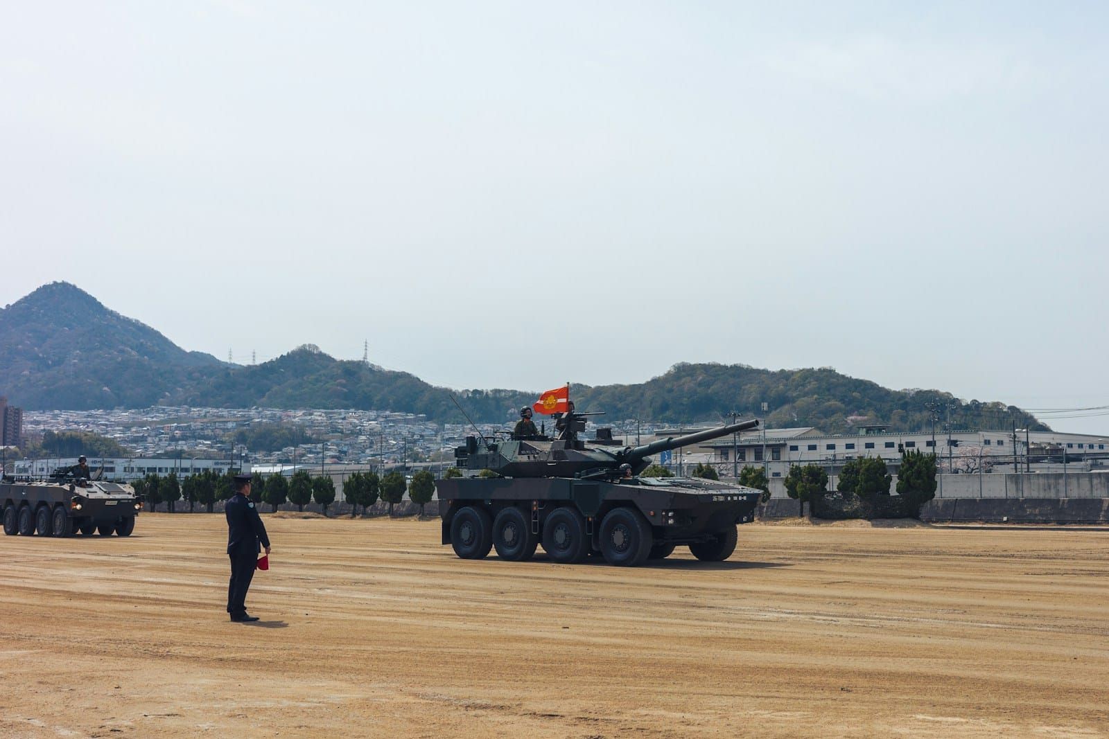 A line of armoured military vehicles drawn up on open sandy ground with hills on the horizon.