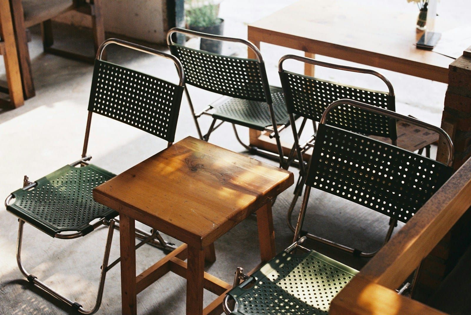 Two identical wooden chairs sit side by side against a minimal neutral interior, empty and precisely aligned.