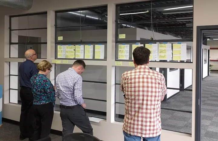 Four people reviewing papers stuck to a window.