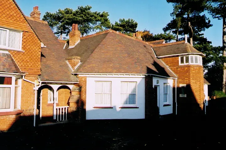 A long red brick building with brown roof and painted white trim.