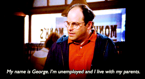 A balding man with glasses wearing a red shirt and blue coat. Subtitles on the GIF say "My name is George. I'm unemployed and I live with my parents."