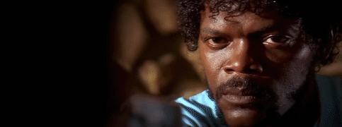 A Black man with moustache and curly hair, talking.