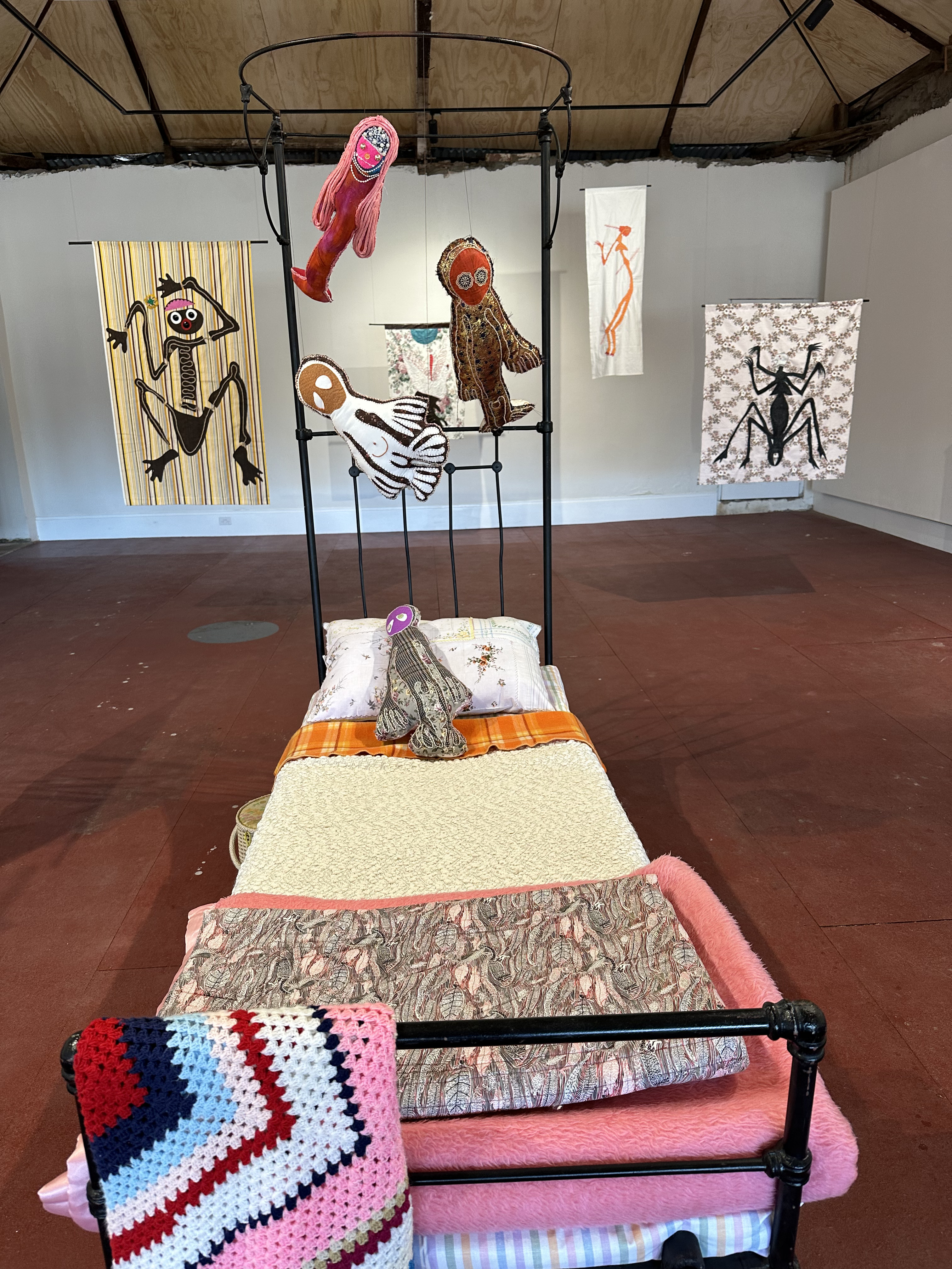 A view of the exhibition looking from the foot of the bed