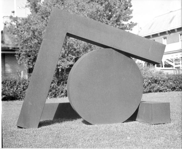 A black and white photograph of a geometric sculpture, a round flat disk and a square armature encircling it.