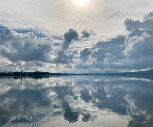 Large lake with clouds and sky perfectly mirrored in the water