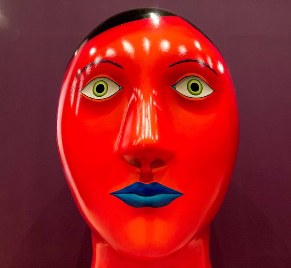 Large red painted head with black hair, green eyes, and blue lips