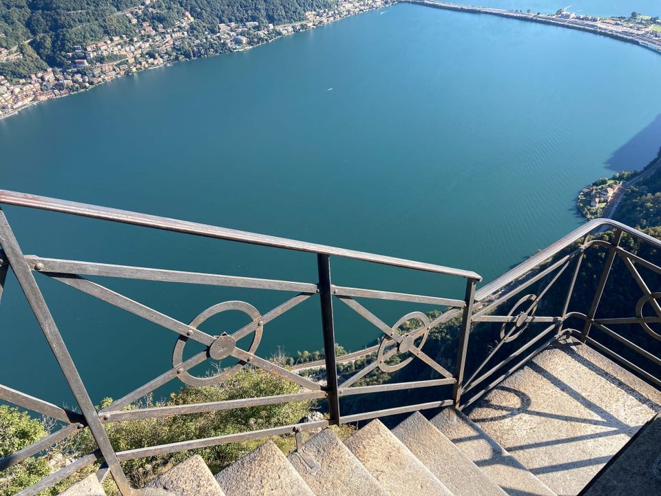 A narrow staircase overlooking a precipitous drop-off over a cliff by a lake