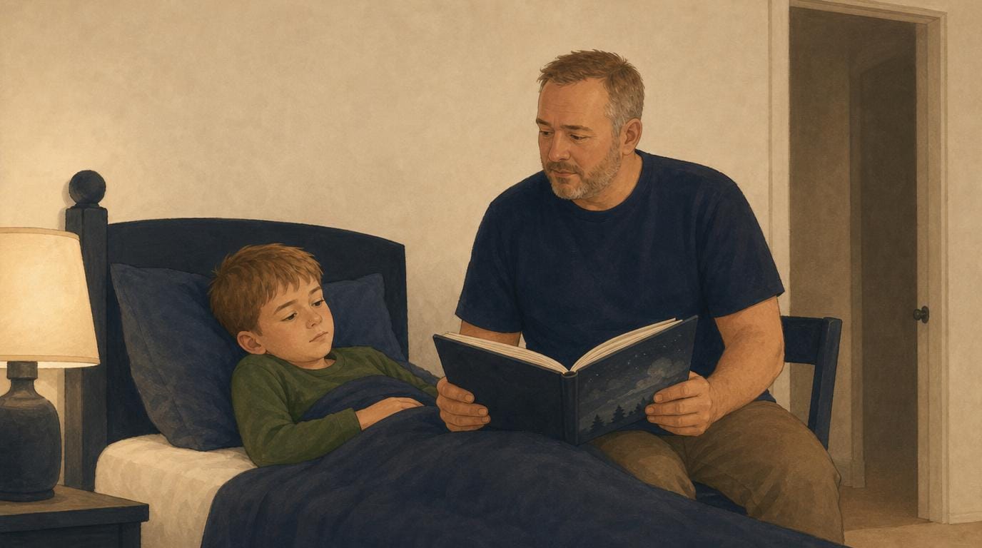 A father sits on the edge of the bed reading one book to his son at bedtime, lamp-lit and calm.