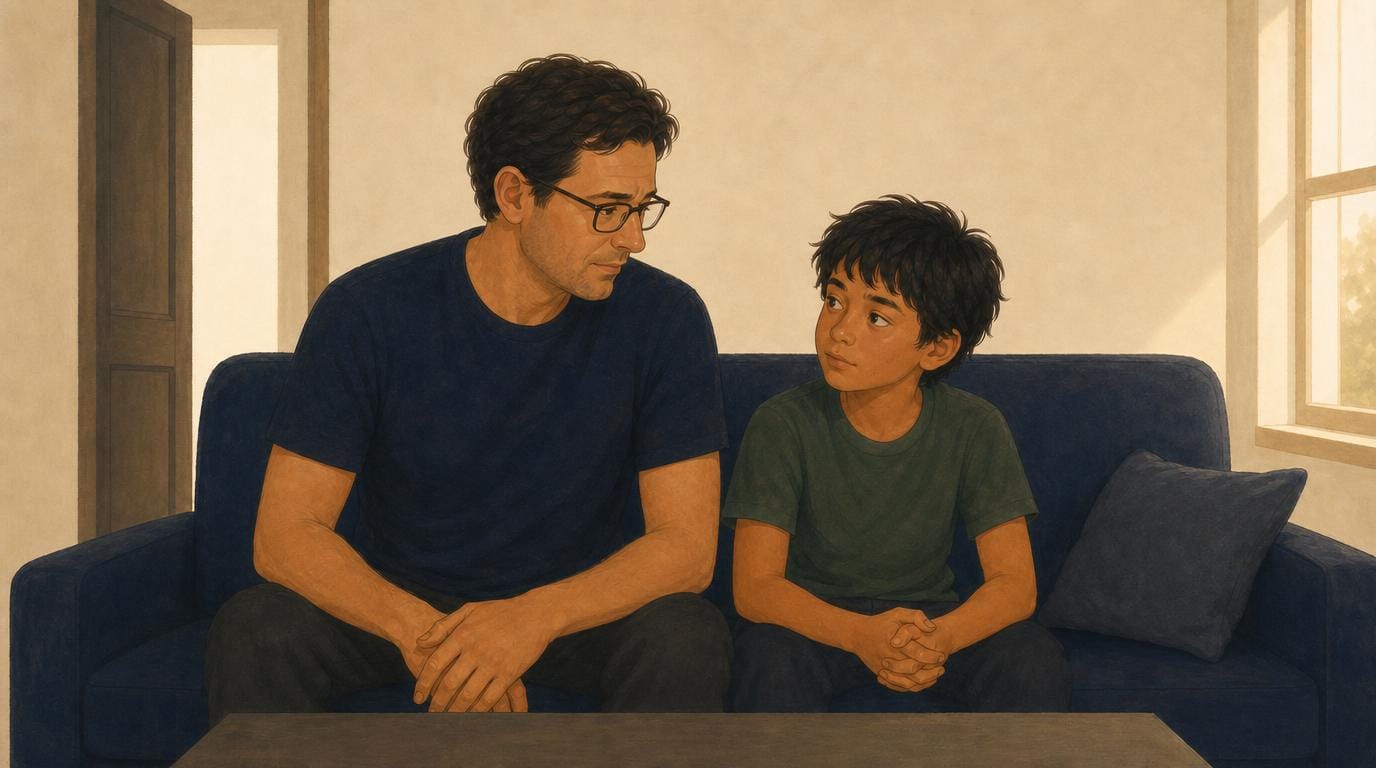 A father and his look-alike son sit side by side on the sofa in the same posture, hands clasped, looking at each other.