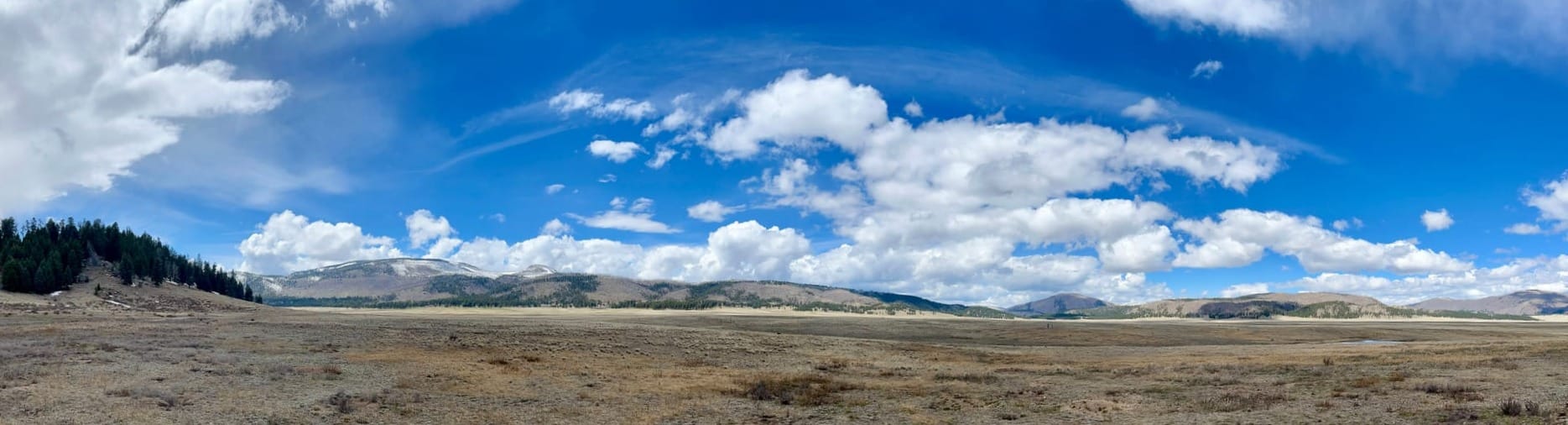 A broad, flat valley surrounded by mountains, under partly cloudy skies.
