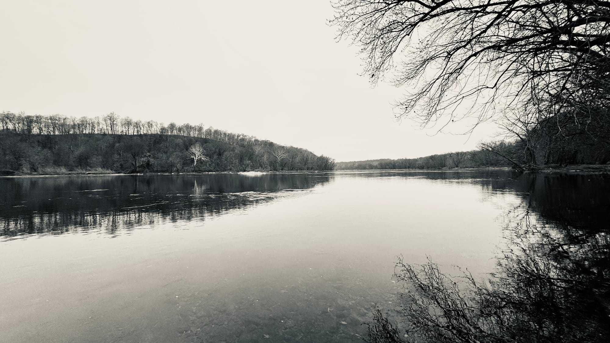 A river flows between forested banks under a blanket of clouds.