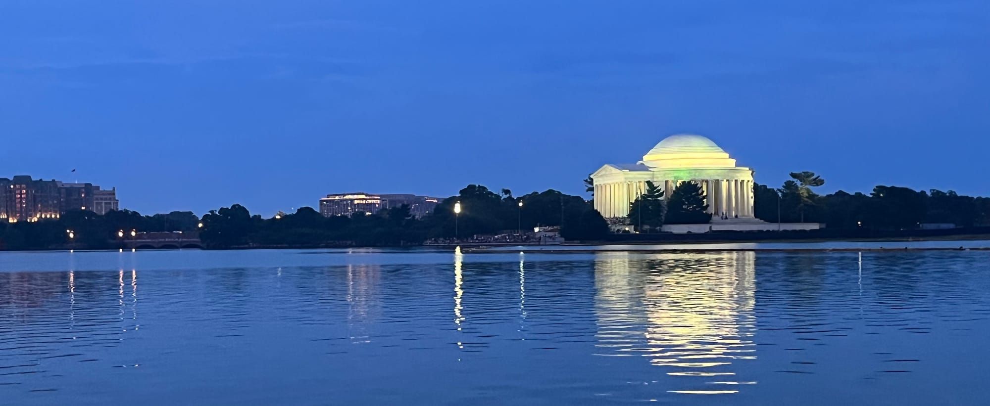 A building with a dome (Jefferson Memorial) lit against a dark sky, reflected on water (Tidal Basin).