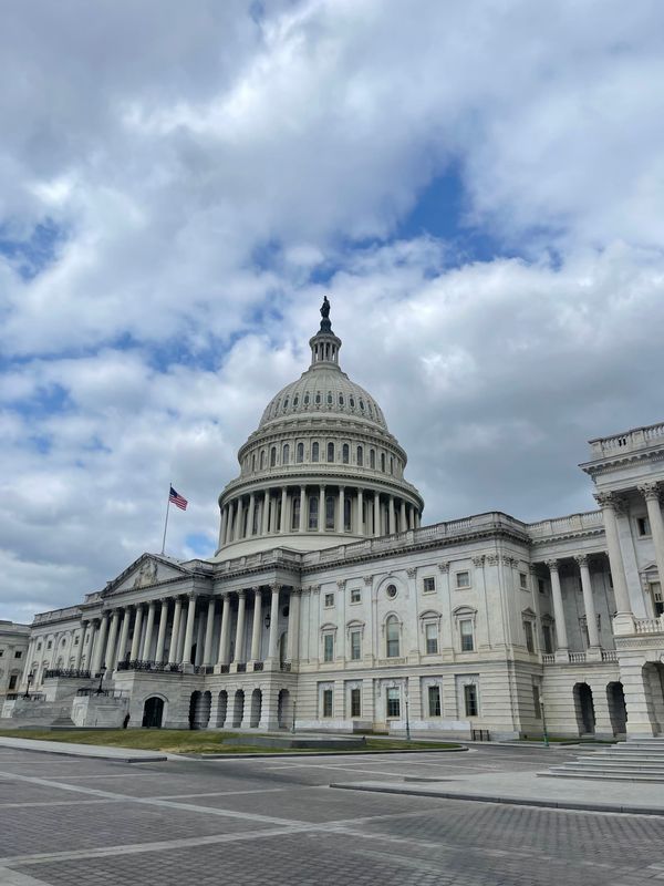 The US Capitol dome under mostly cloudy skies.