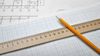 A building plan, ruler, pencil and graphing paper on a table