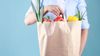Grocery bag filled with fresh produce being held by a person