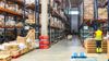 A worker inside a warehouse with many shelves full of boxes