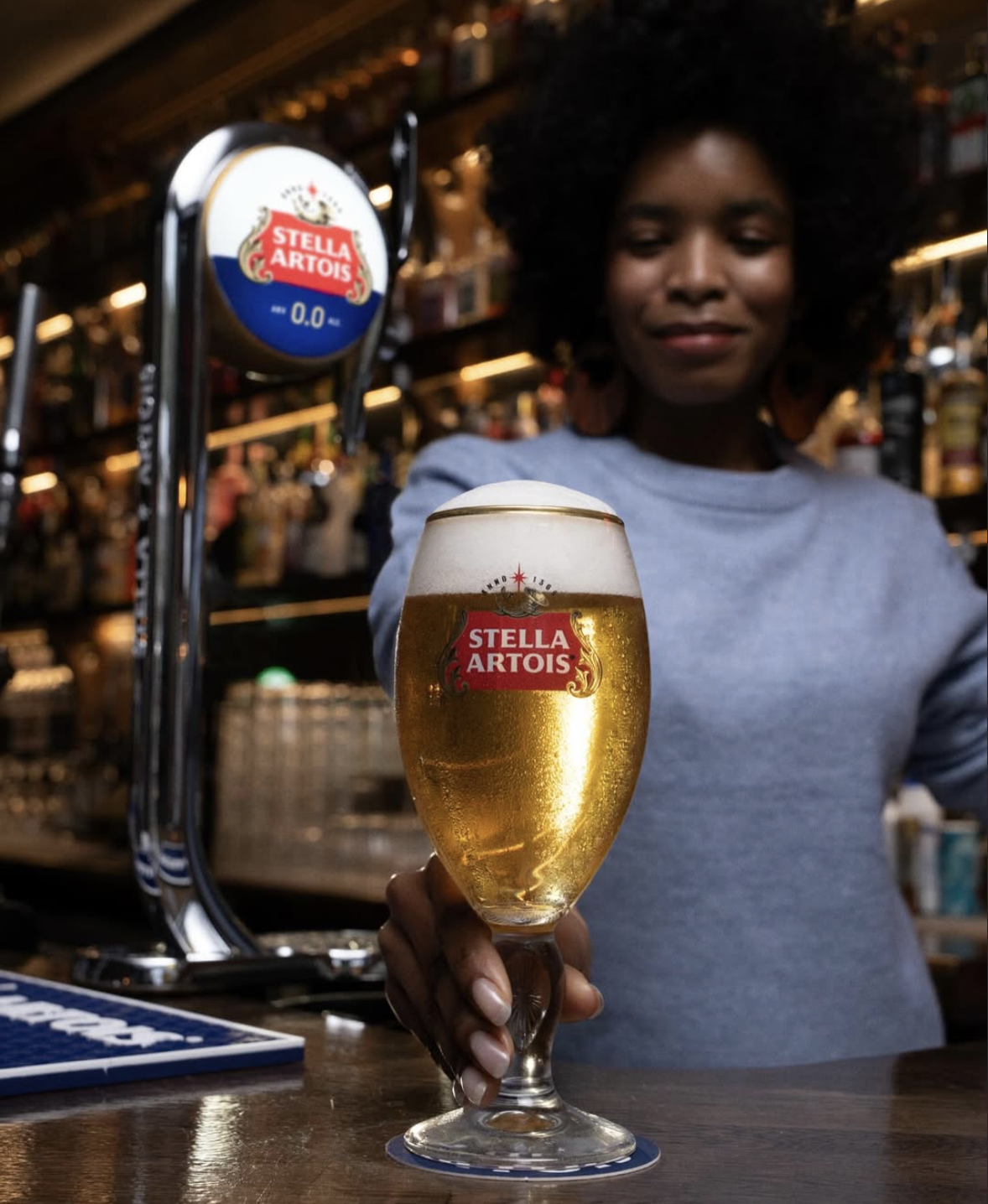 a lady holding a pint of Stella Artois 0% alcohol in a pub