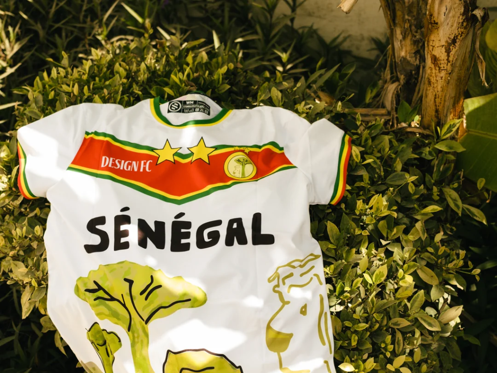 A white Senegal kit with hand-drawn type of SENEGAL with illustrations of baobob trees.