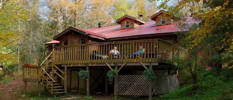 The timber Algonquin Eco-Lodge with its red metal roof set among autumn forest, Ontario, Canada