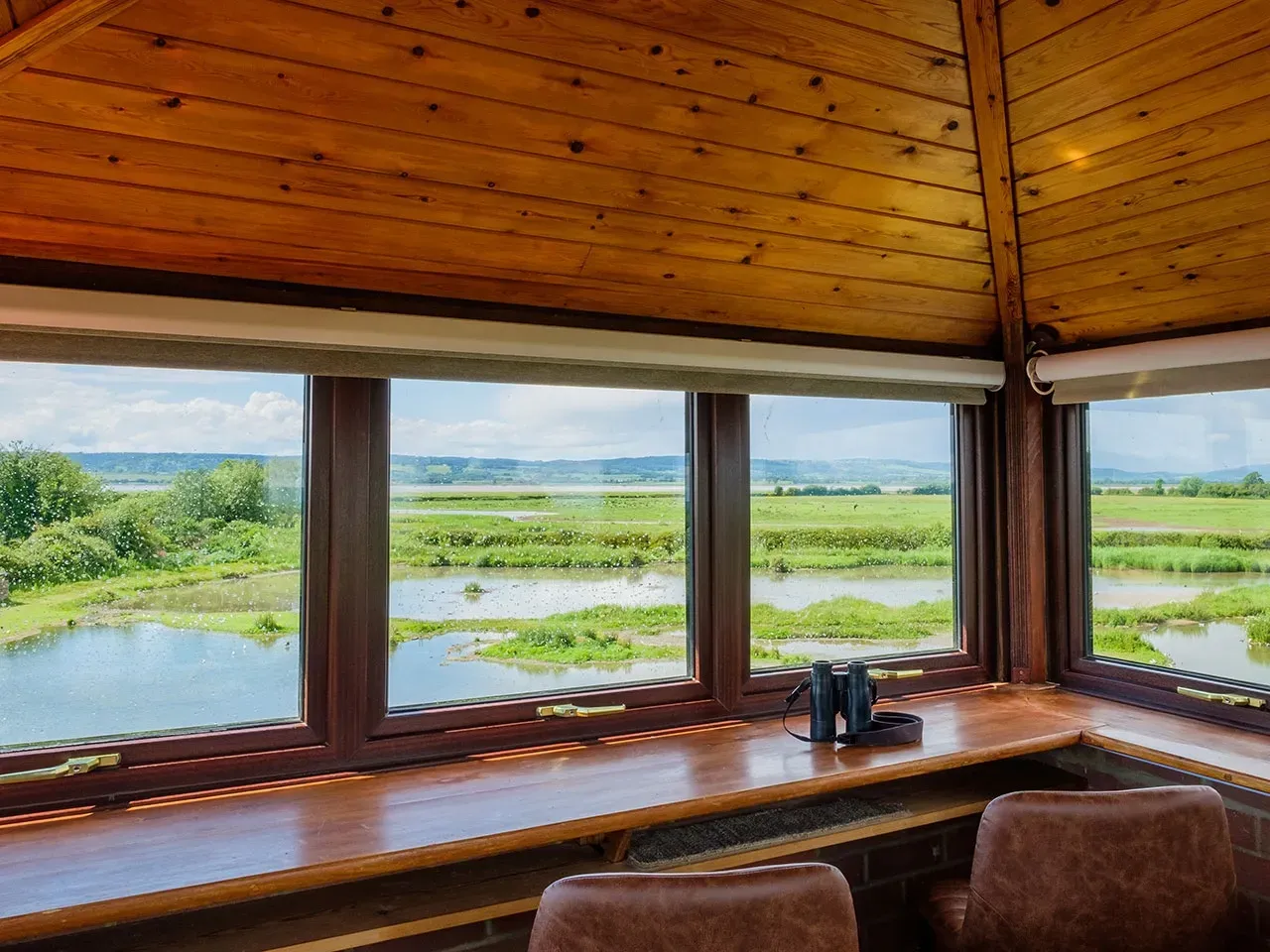 The view over wetland pools from inside a timber bird hide at Slimbridge Wetland Centre, United Kingdom