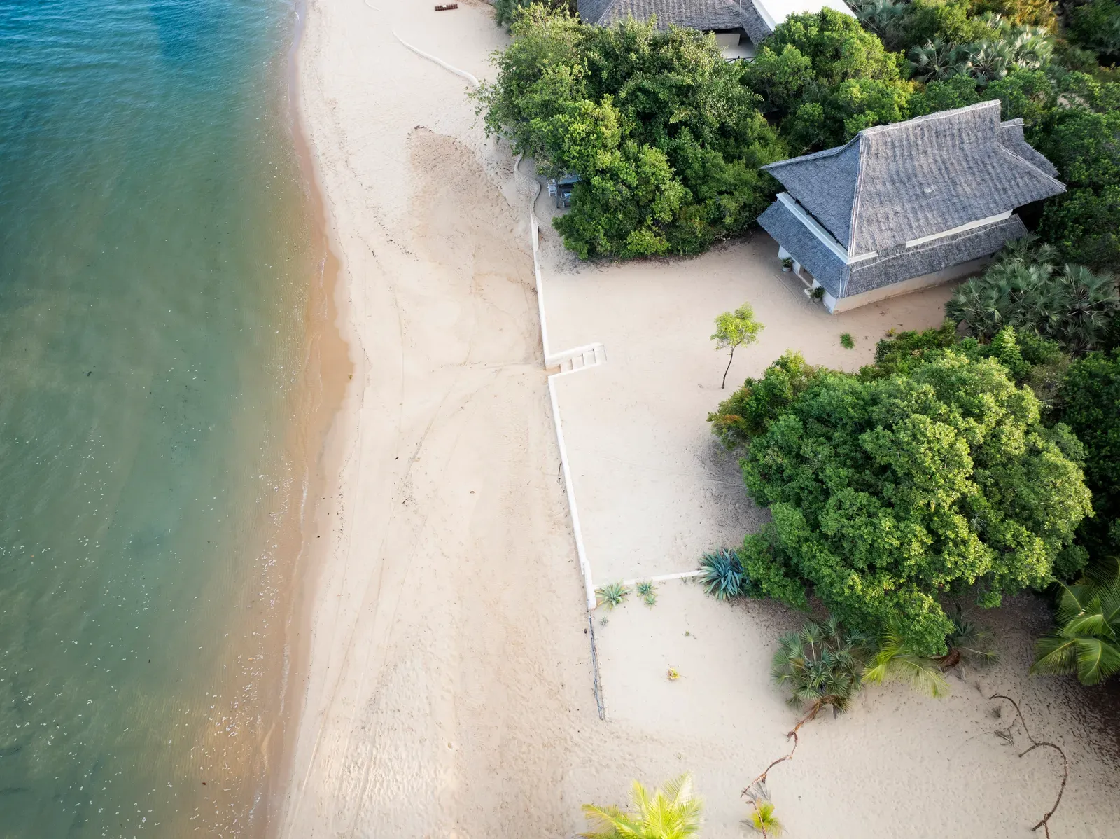 Palm-thatched Swahili banda set among coastal vegetation at The Cabanas Lamu, Kizingoni Beach, Kenya