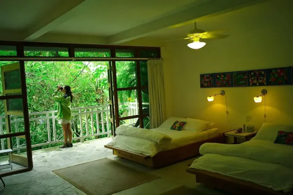 A traveler watches birds with binoculars from a garden-view room at Canopy Lodge, Panama