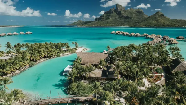 Aerial view of Four Seasons Bora Bora's overwater bungalows and lagoon beneath Mount Otemanu