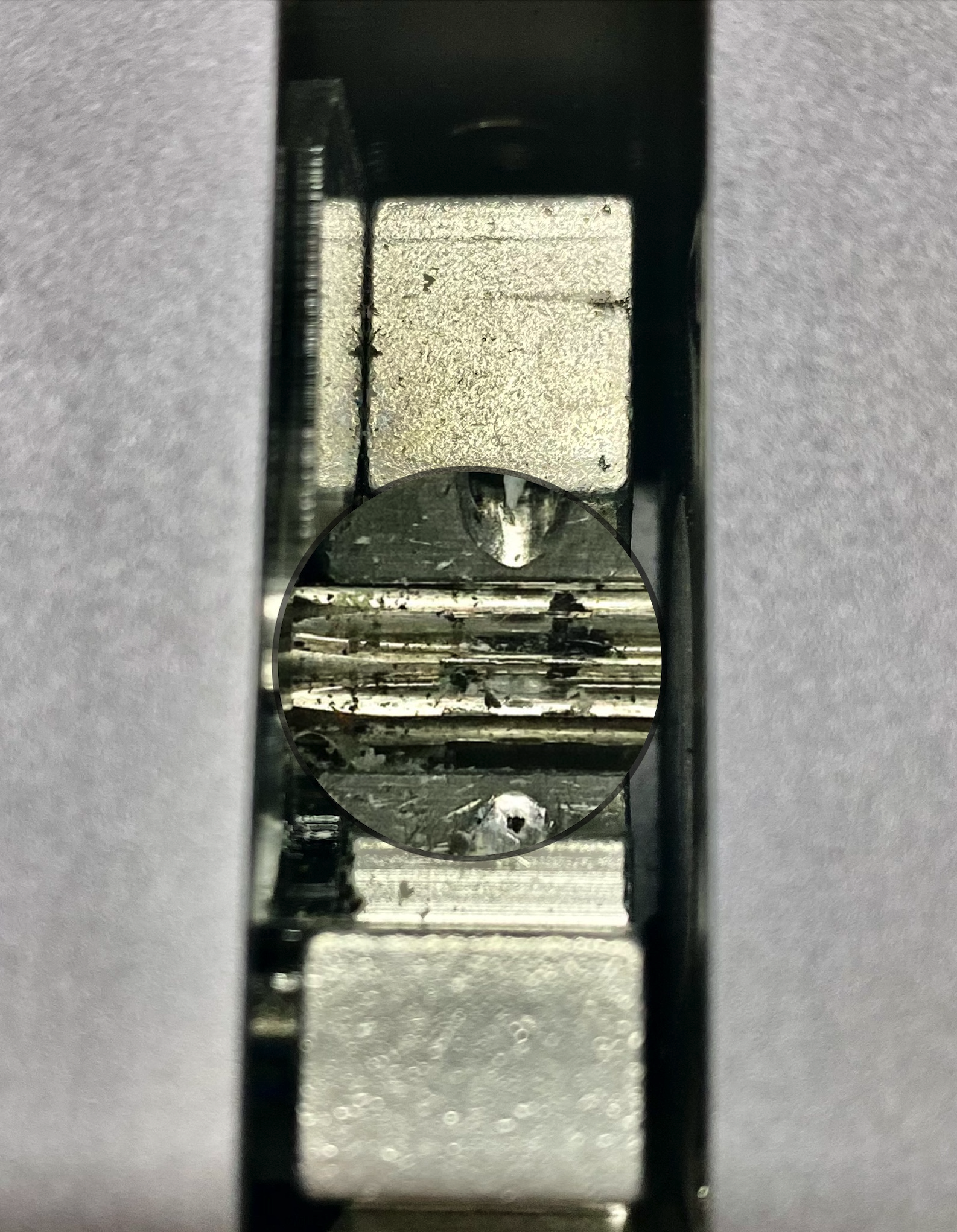 A close-up view of a 3D printer's extruder gears, showing visible debris and filament residue between the gear teeth. This image illustrates a common sign of a partially clogged nozzle, where filament extrusion issues can result from buildup in the gears.